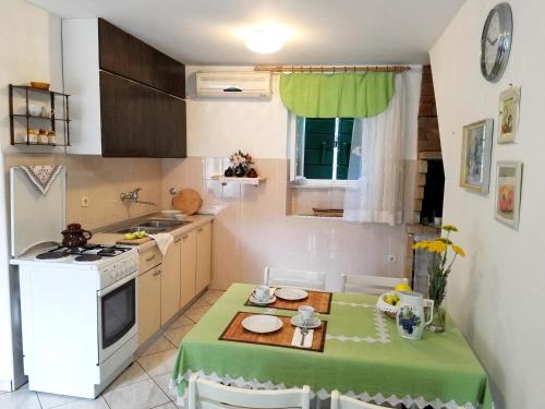 a small kitchen with a table with a green table cloth at Holiday house with WiFi Dol, Brac - 5674 in Postira