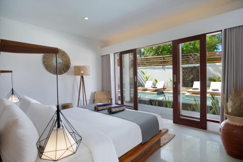 a bedroom with a bed and a view of a pool at Villa Sakura. Luxury 3 Bedroom Villa. in Selong Belanak