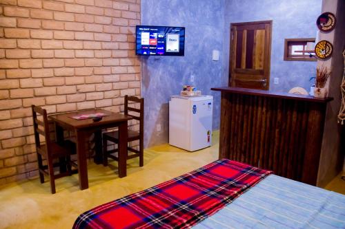 a room with a bed and a table and a small kitchen at Chalé 01 Itaipu Vale da Colina Niterói in Niterói