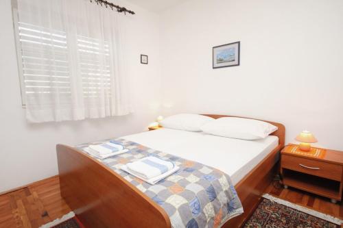 沃迪采的住宿－Apartments with a parking space Vodice - 5890，一间卧室配有一张带白色床单的床和一扇窗户。