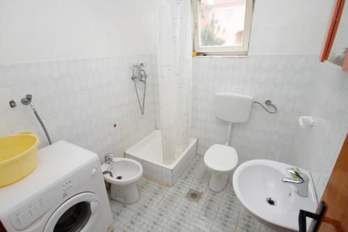 La salle de bains blanche est pourvue d'un lavabo et de toilettes. dans l'établissement Apartments by the sea Vrsi - Mulo, Zadar - 5790, à Vrsi
