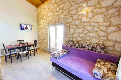 GdinjにあるSeaside secluded apartments Cove Skozanje, Hvar - 5713の紫色のソファと石壁のリビングルーム