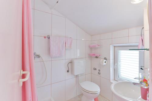 a white bathroom with a toilet and a sink at Apartments with a parking space Rtina - Stosici, Zadar - 5881 in Ražanac