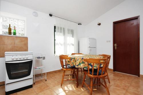 een keuken met een tafel en stoelen en een fornuis bij Seaside secluded apartments Cove Zavala - Gdinj, Hvar - 5717 in Bogomolje