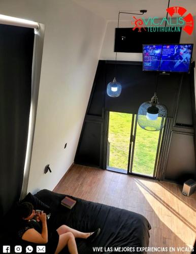 a woman sitting on a couch in a living room at Vicalis Hotel, Villas y Glamping in San Sebastian Xolalpa