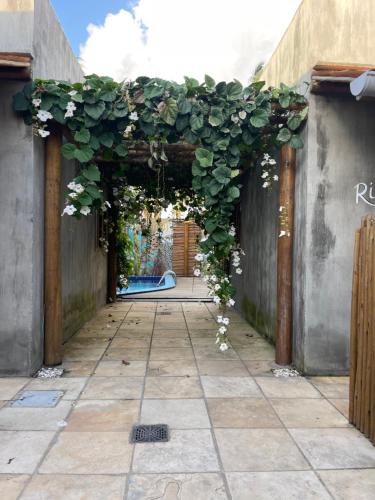an entrance to a building with an arch covered in ivy at Chalé Palhano Beach in São Miguel dos Milagres