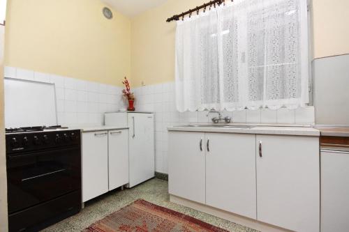 une cuisine avec des armoires blanches et un appareil noir dans l'établissement Apartments with a parking space Biograd na Moru, Biograd - 5899, à Biograd na Moru