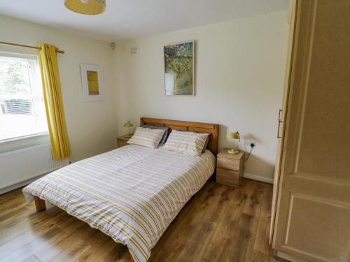 1 dormitorio con 1 cama con manta a rayas y ventana en 2 Castle Cove, en Drumahayre