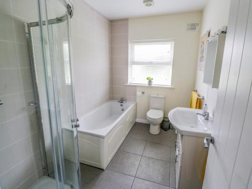 uma casa de banho com uma banheira, um WC e um lavatório. em 2 Castle Cove em Drumahayre