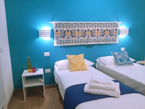 een kamer met 2 bedden en een blauwe muur bij Camera Olbia Centro, vacanze Olbia e dintorni in Olbia