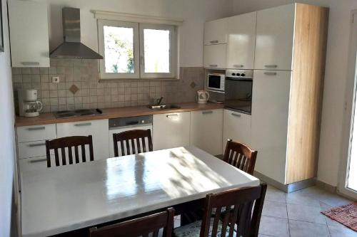 cocina con armarios blancos, mesa y sillas en Seaside holiday house Zaton, Zadar - 5910, en Zaton