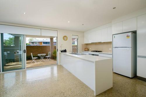 a kitchen with white cabinets and a white refrigerator at Splendour on Sackville in Albury