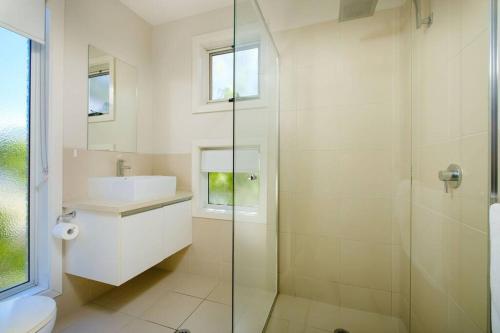 a bathroom with a glass shower and a sink at Splendour on Sackville in Albury