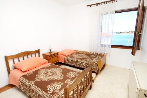 dwa łóżka w pokoju z oknem w obiekcie Apartments by the sea Kali, Ugljan - 5828 w mieście Kali