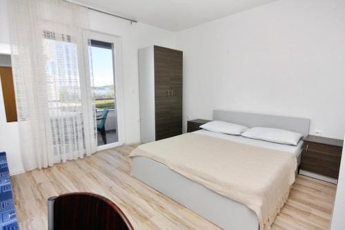ein weißes Schlafzimmer mit einem Bett und einem großen Fenster in der Unterkunft Apartments by the sea Bibinje, Zadar - 5916 in Bibinje