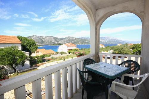 a balcony with a table and chairs and a view of the water at Apartments by the sea Kneza, Korcula - 4342 in Račišće