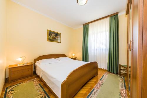 Schlafzimmer mit einem Bett und einem Fenster mit grünen Vorhängen in der Unterkunft Apartments with parking spaces Zadar - Diklo, Zadar - 5809 in Zadar