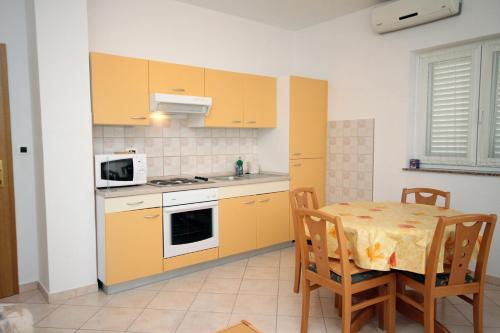 eine Küche mit gelben Schränken und einem Tisch mit Stühlen in der Unterkunft Apartment Vrsi - Mulo 5860b in Nin