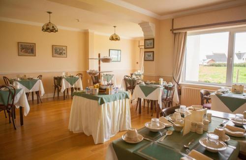 una sala da pranzo con tavoli, sedie e una finestra di Bambury's Guesthouse a Dingle
