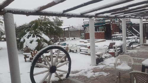 un patio cubierto de nieve con una rueda de carruaje de madera en Cabañas Lugar Escondido en Mendoza