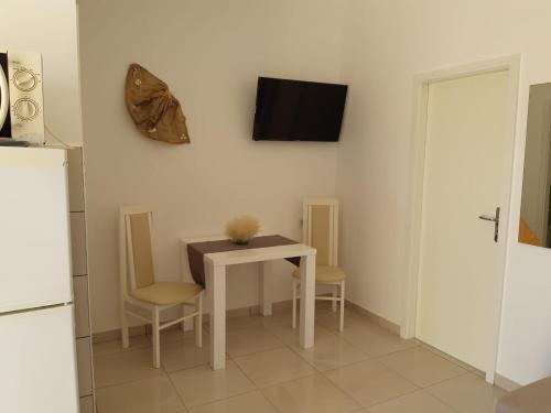 a kitchen with a table and chairs and a tv on the wall at Apartments by the sea Vrsi - Mulo, Zadar - 5859 in Vrsi