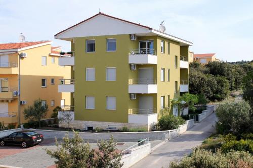 un immeuble jaune avec une voiture garée devant dans l'établissement Apartments by the sea Kozino, Zadar - 5755, à Petrčane