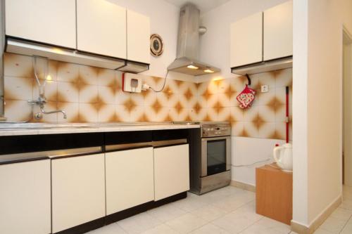 a kitchen with white cabinets and a stove at Apartments and rooms with parking space Korcula - 4399 in Korčula