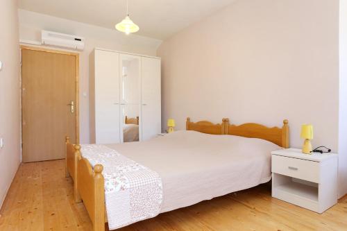 a bedroom with a white bed and a wooden floor at Studio Zuljana 4576c in Žuljana
