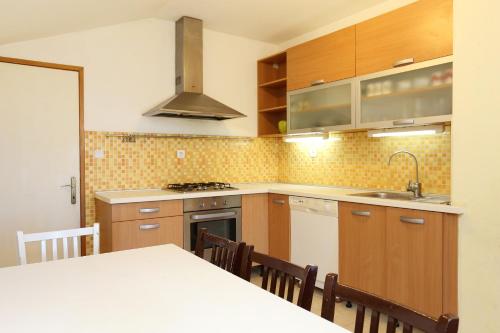 uma cozinha com armários de madeira e uma mesa com cadeiras em Apartment Zuljana 4576a em Žuljana