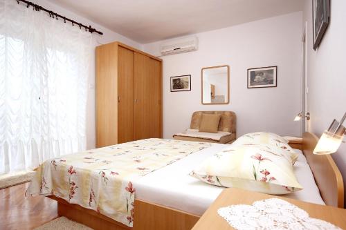 een slaapkamer met een bed, een stoel en een raam bij Apartment Orebic 4525c in Orebić