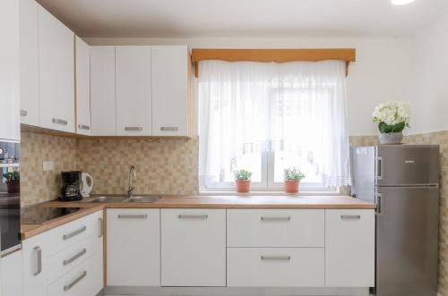 a kitchen with white cabinets and a stainless steel refrigerator at Family friendly seaside apartments Orebic, Peljesac - 4537 in Orebić