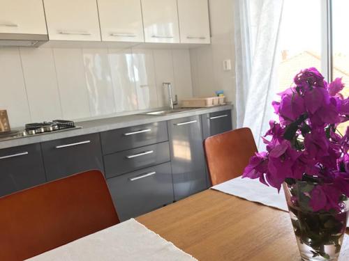 Apartments and rooms by the sea Orebic, Peljesac - 4563 في أوربيك: مطبخ مع طاولة مع الزهور الأرجوانية في مزهرية