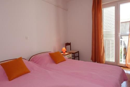 sypialnia z łóżkiem z pomarańczowymi poduszkami i oknem w obiekcie Apartments and rooms with parking space Nin, Zadar - 5805 w Nin