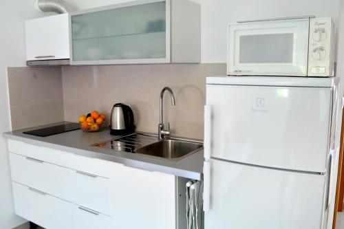 a white kitchen with a sink and a refrigerator at Apartments by the sea Orebic, Peljesac - 4563 in Orebić