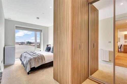 a bedroom with a bed and a large glass door at Riverside apartment minutes from Elizabeth line in London