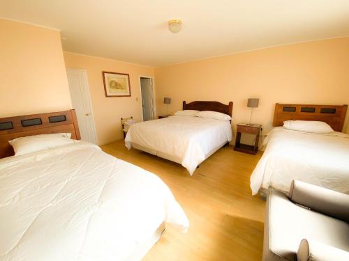 a bedroom with two beds and wooden floors at Hotel Londres La Serena in La Serena