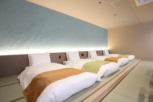 a row of four beds in a room at 宮若温泉郷 宮若虎の湯 Miyawaka Toranoyu in Miyawaka