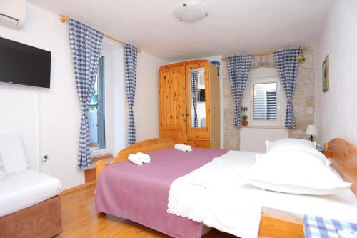 a bedroom with a bed and a tv and two windows at Apartments with a parking space Omis - 4327 in Omiš