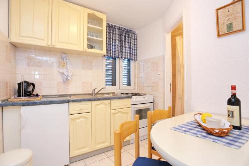 a kitchen with yellow cabinets and a table with a bottle of wine at Apartments with a parking space Omis - 4327 in Omiš