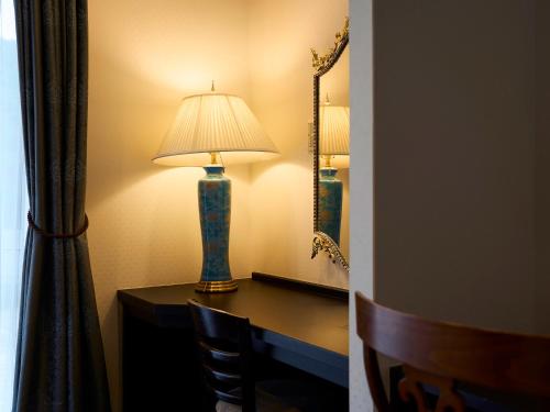 a lamp on a desk in a room with a mirror at Hotel Flags Kuju Kusima in Sasebo