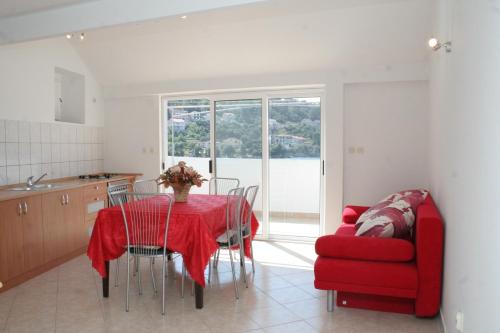 a kitchen and dining room with a table and a red chair at Apartments by the sea Brna, Korcula - 4415 in Smokvica