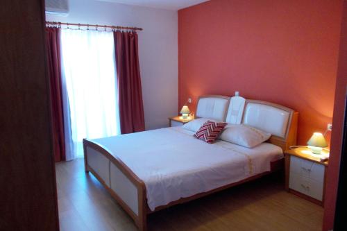 ein Schlafzimmer mit einem weißen Bett und einer roten Wand in der Unterkunft Apartment Kneza 4342a in Račišće