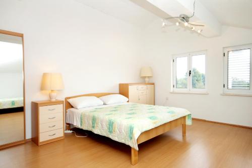 ein weißes Schlafzimmer mit einem Bett und zwei Fenstern in der Unterkunft Apartments with a parking space Korcula - 4433 in Korčula