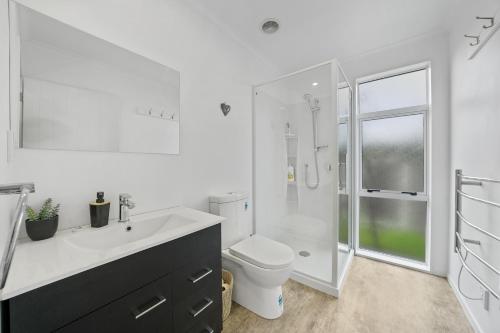 a white bathroom with a toilet and a shower at Treasure on Tuscan - Martinborough Holiday Home in Martinborough 
