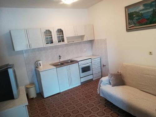 a small kitchen with white cabinets and a couch at Apartments by the sea Grscica, Korcula - 4487 in Prizba
