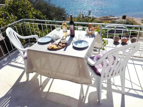 een witte tafel met twee stoelen en twee flessen wijn bij Apartments by the sea Lumbarda, Korcula - 4369 in Lumbarda