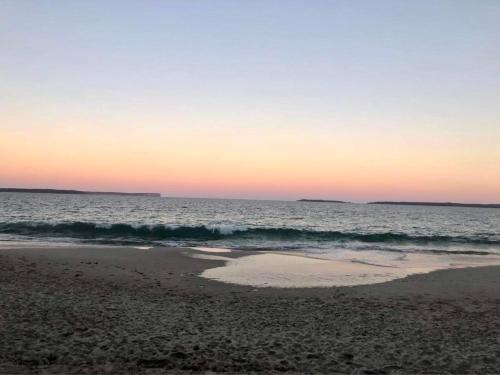 a sunset over the ocean with a sandy beach at The Husky House or Little Husky Studio Suite in Huskisson