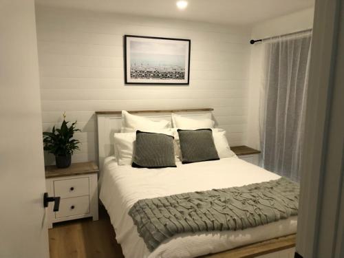 a bedroom with a bed with white sheets and pillows at Jetty Road Beach House in Rosebud