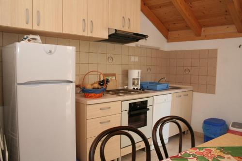 a kitchen with a white refrigerator and a table with chairs at Apartment Vrboska 4601c in Vrboska