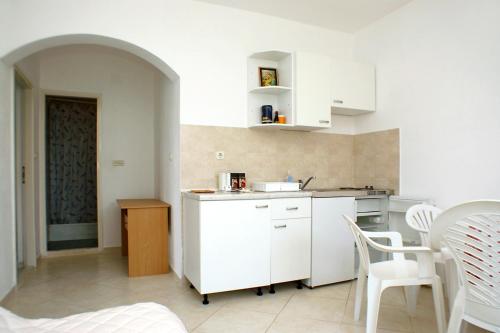 a kitchen with white cabinets and a table and chairs at Apartments by the sea Luka Dubrava, Peljesac - 4568 in Janjina